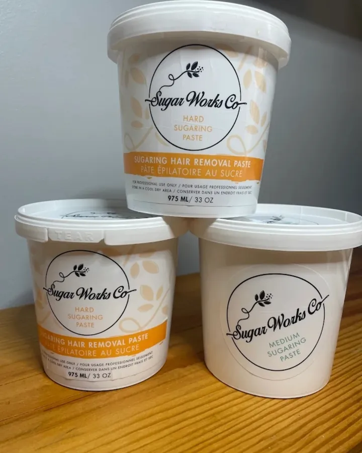 Three tubs of sugaring paste stacked on a wooden shelf